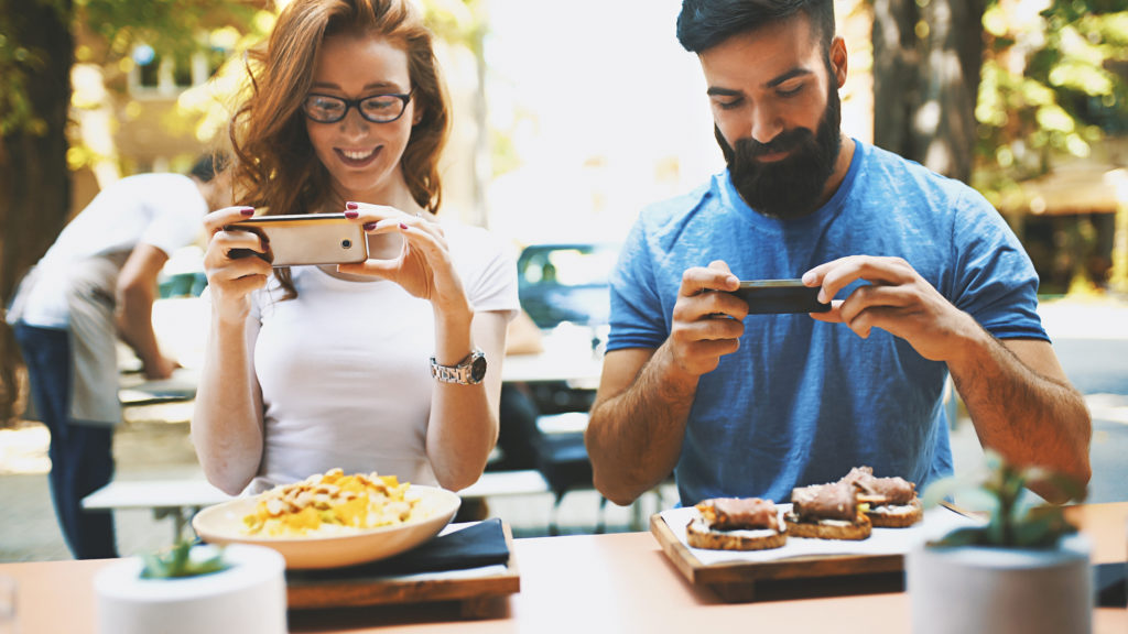 A couple at a restaurant taking shots of their meal